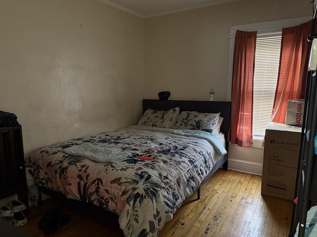 bedroom featuring light hardwood / wood-style flooring, multiple windows, and crown molding