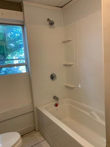 bathroom featuring tile patterned flooring, toilet, and tub / shower combination