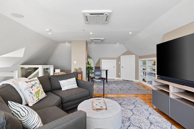 living area with vaulted ceiling, wood finished floors, built in shelves, and baseboards