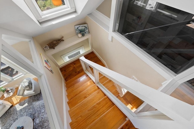 staircase with a skylight and wood finished floors