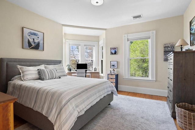 bedroom featuring light wood-style flooring, multiple windows, and baseboards