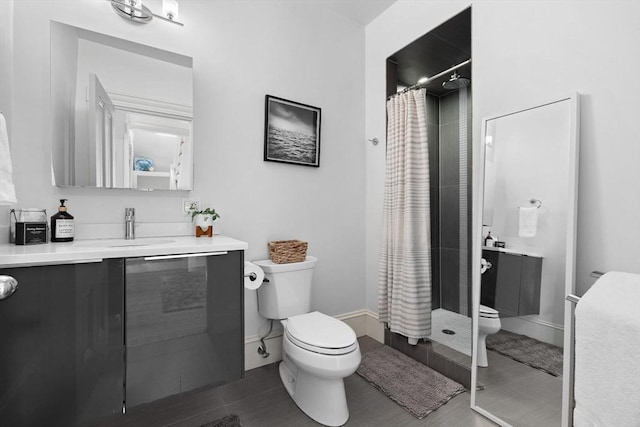 full bathroom with toilet, vanity, a shower stall, and baseboards