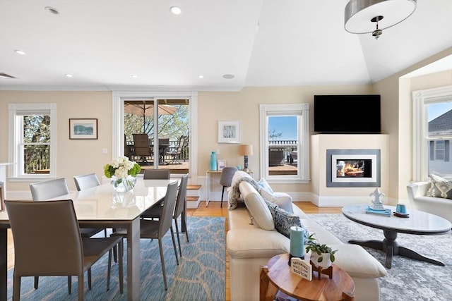 living area featuring healthy amount of natural light, wood finished floors, a glass covered fireplace, recessed lighting, and lofted ceiling