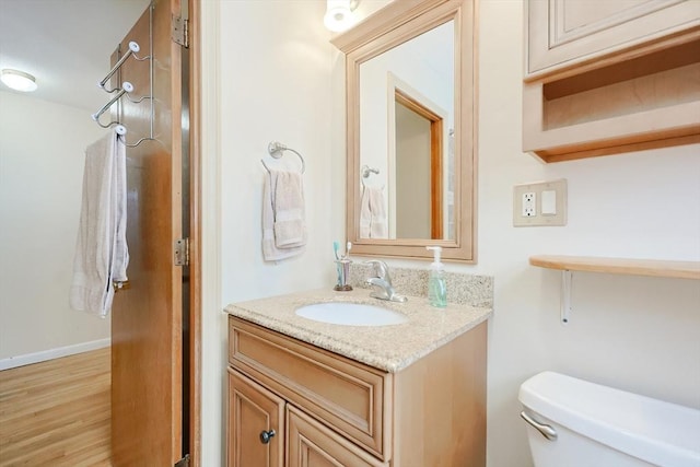 bathroom featuring toilet, wood-type flooring, and vanity