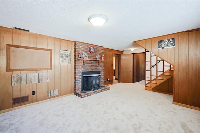 unfurnished living room with light carpet, a wood stove, and wooden walls