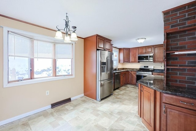 kitchen with ornamental molding, stainless steel appliances, pendant lighting, and dark stone countertops