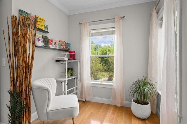 sitting room featuring wood finished floors, crown molding, plenty of natural light, and baseboards