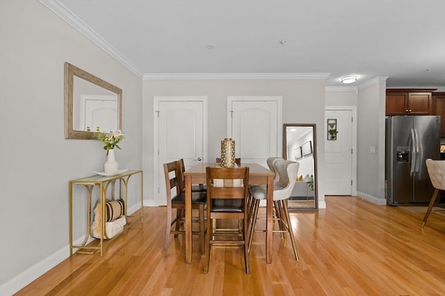 dining room featuring light wood-style floors, baseboards, and crown molding