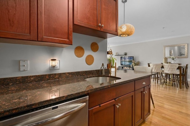 kitchen featuring stainless steel dishwasher, a sink, crown molding, dark stone counters, and light wood-style flooring