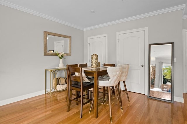 dining area with ornamental molding, light wood finished floors, and baseboards
