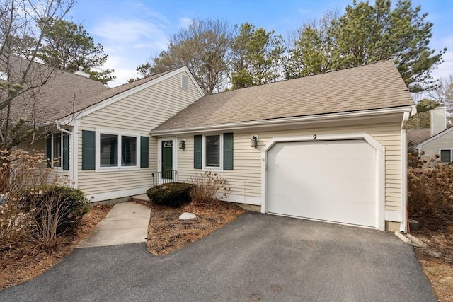 ranch-style house featuring driveway, roof with shingles, and an attached garage