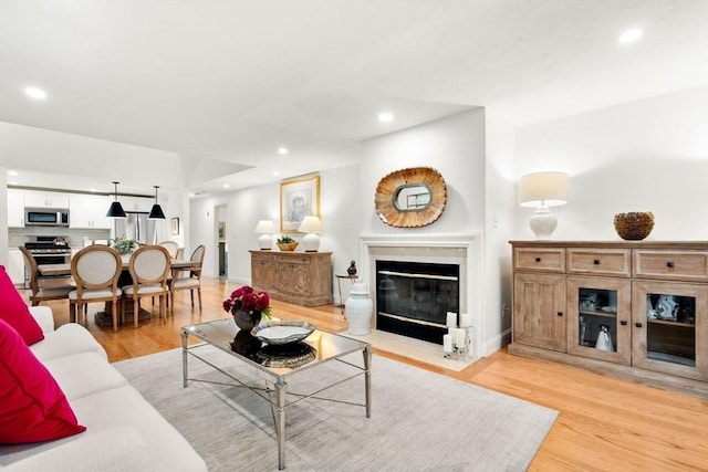 living room with a fireplace with flush hearth, recessed lighting, and light wood-type flooring