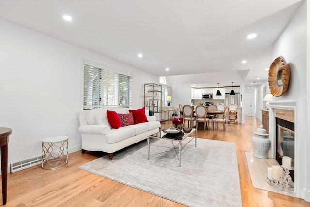 living room with recessed lighting, baseboards, light wood-style floors, and a fireplace