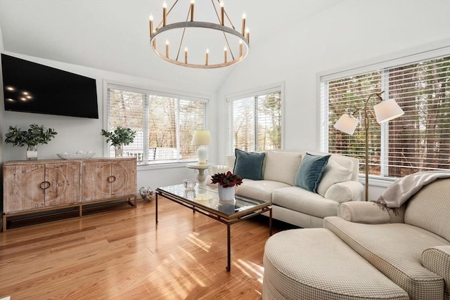 living room with vaulted ceiling, light wood-type flooring, and a chandelier