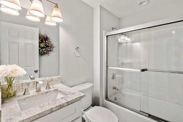 bathroom featuring vanity, toilet, and bath / shower combo with glass door