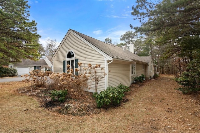 view of side of home featuring a chimney and a shingled roof