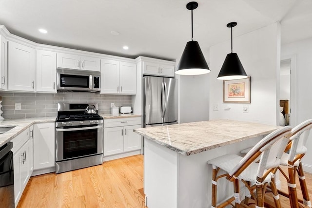 kitchen with white cabinets, light wood-type flooring, and stainless steel appliances