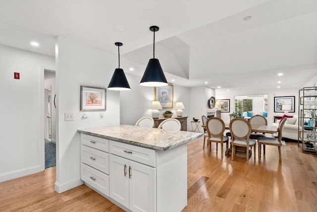 kitchen featuring light stone countertops, recessed lighting, light wood-style flooring, hanging light fixtures, and white cabinetry