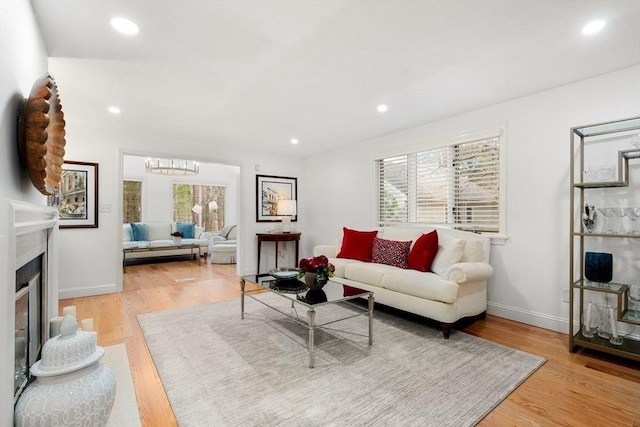 living area with a wealth of natural light, wood finished floors, and a fireplace with raised hearth