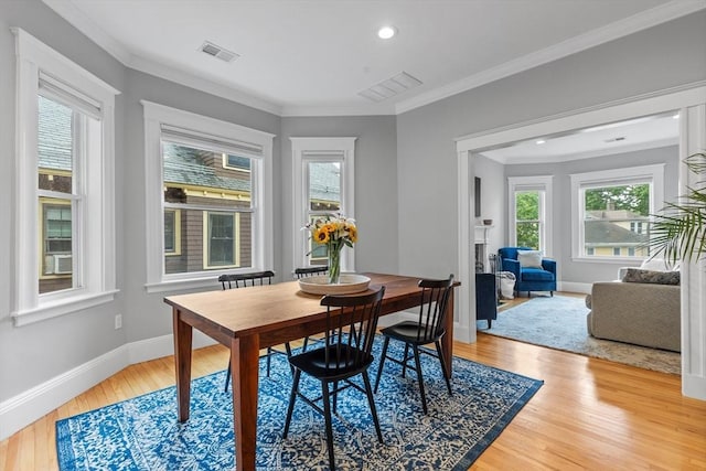 dining room featuring light wood-style flooring, baseboards, crown molding, and recessed lighting