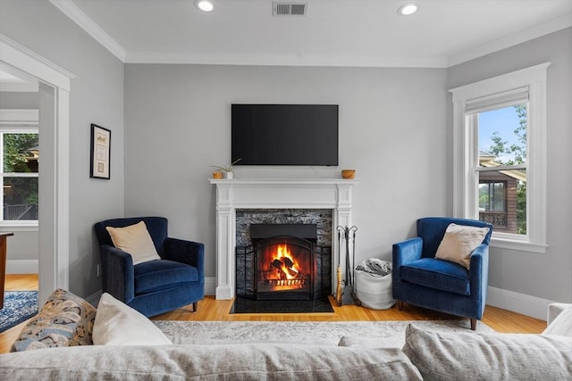 living room featuring a premium fireplace, plenty of natural light, ornamental molding, recessed lighting, and wood finished floors