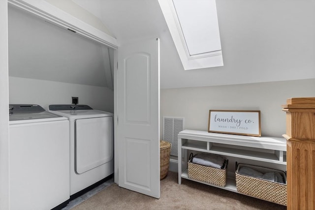 laundry area featuring washing machine and dryer, a skylight, and light colored carpet