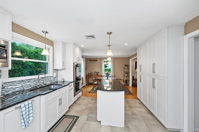 92 Gregory St, Waltham, MA 02451 - kitchen with tasteful backsplash, white cabinetry, appliances with stainless steel finishes, dark stone countertops, and pendant lighting