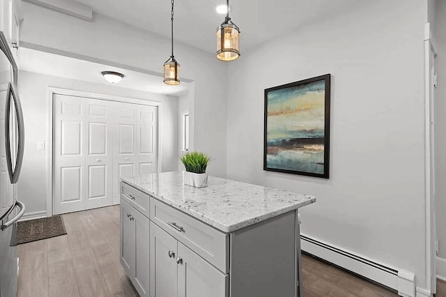 61 E Main, Merrimac, MA 01860 - kitchen featuring a baseboard heating unit, light wood-type flooring, a center island, and light stone counters