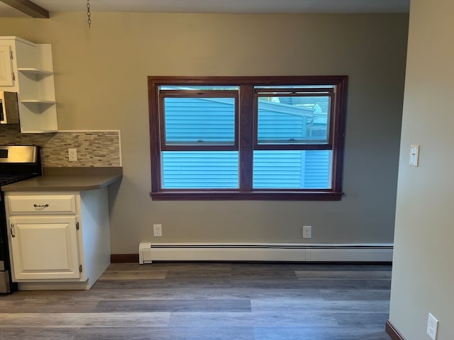 unfurnished dining area featuring light wood-type flooring, a baseboard radiator, and a healthy amount of sunlight