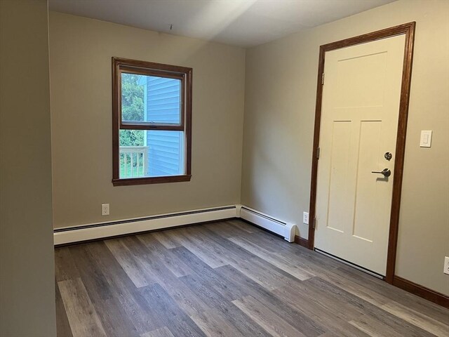 interior space with a baseboard heating unit and wood-type flooring