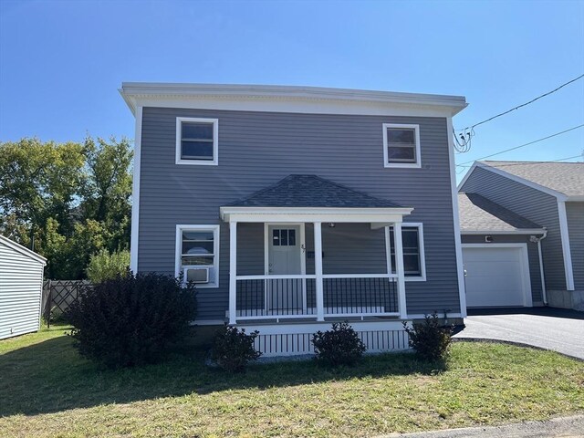 view of front of house with cooling unit, a front lawn, a garage, and covered porch