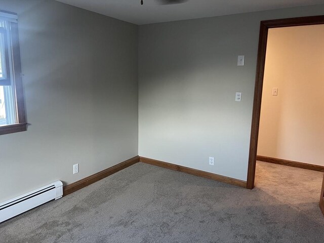 empty room featuring a healthy amount of sunlight, a baseboard radiator, and ceiling fan