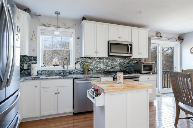 kitchen featuring stainless steel appliances, light wood-style floors, white cabinets, a sink, and butcher block countertops