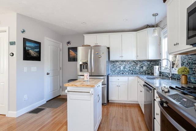 kitchen featuring decorative backsplash, light wood-style flooring, stainless steel appliances, wooden counters, and a sink