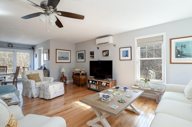 living area with light wood finished floors, ceiling fan, baseboards, and an AC wall unit