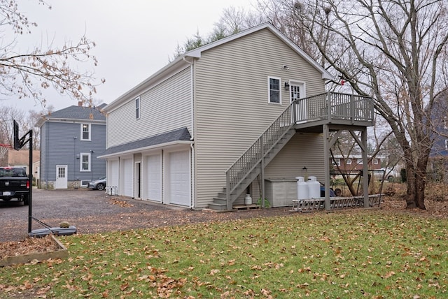 rear view of house featuring a lawn, a garage, and a wooden deck