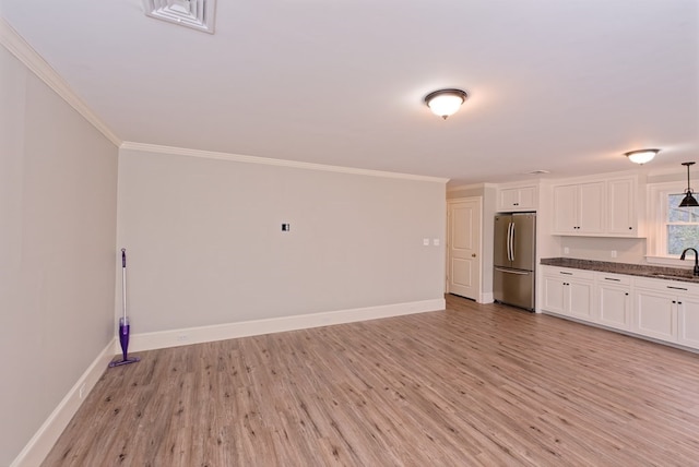 kitchen featuring white cabinets, light hardwood / wood-style flooring, stainless steel refrigerator, and sink