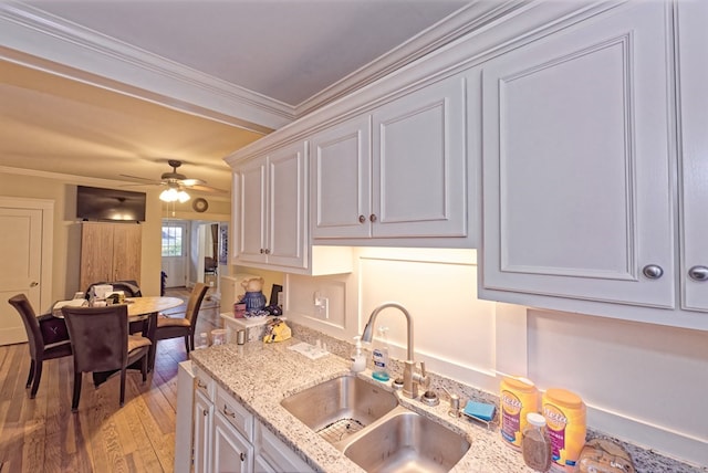 kitchen with crown molding, white cabinetry, sink, and light hardwood / wood-style floors