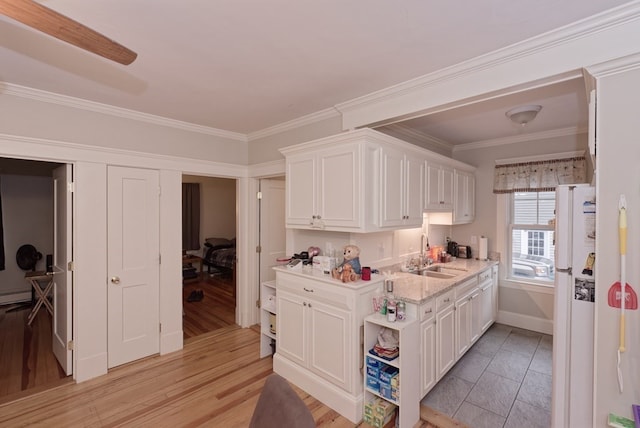 kitchen with light stone countertops, sink, light hardwood / wood-style flooring, crown molding, and white cabinets