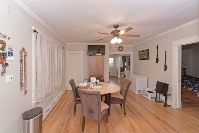 dining space with ceiling fan, a baseboard heating unit, crown molding, and light hardwood / wood-style flooring