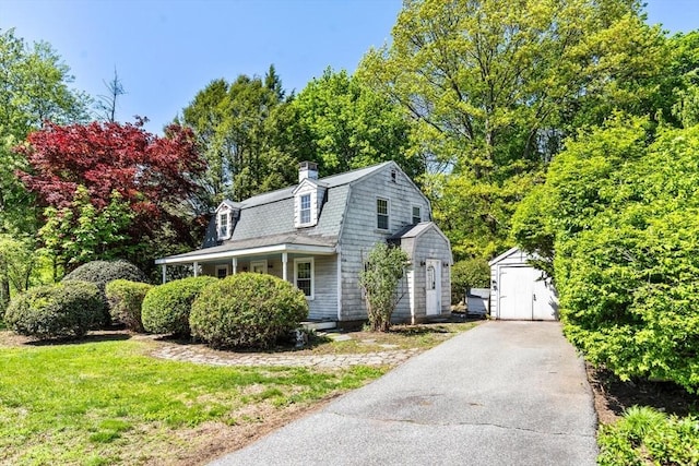 view of front of house featuring a storage shed, a gambrel roof, an outbuilding, and a chimney