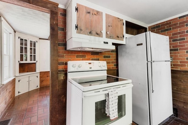 kitchen with white appliances, under cabinet range hood, brick floors, and light countertops