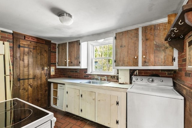 clothes washing area featuring washer / dryer, brick patterned flooring, and cabinet space
