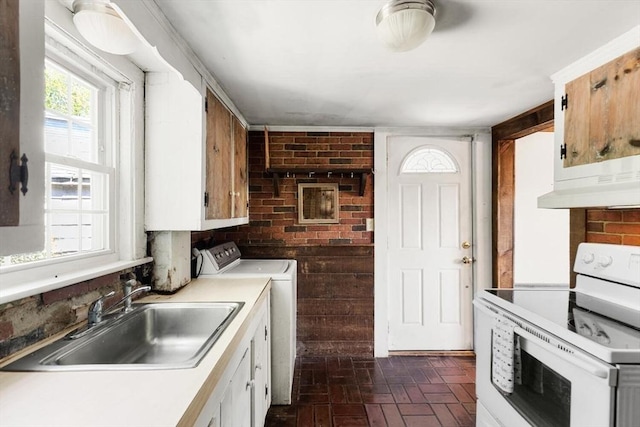 kitchen with electric stove, washer / dryer, a sink, brick patterned floors, and light countertops