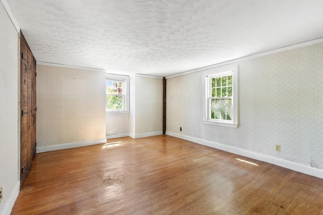 unfurnished room with wood finished floors, crown molding, and baseboards