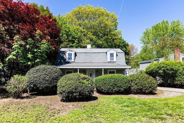 colonial inspired home with a chimney and a front yard