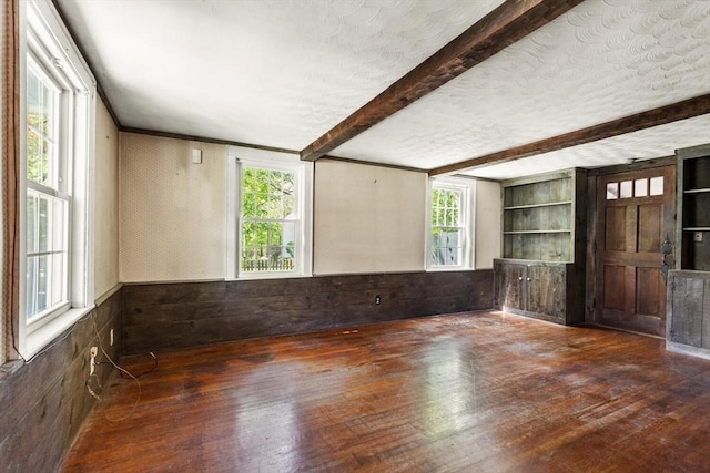 spare room featuring hardwood / wood-style floors, beamed ceiling, wainscoting, and wooden walls