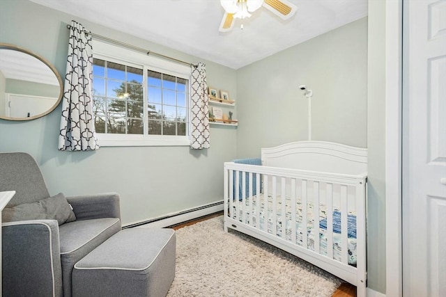 70 Donna Rd, Framingham, MA 01701 - bedroom with a baseboard heating unit, a crib, wood finished floors, and a ceiling fan