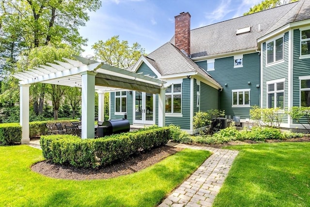 rear view of property featuring a pergola, a chimney, french doors, and a yard