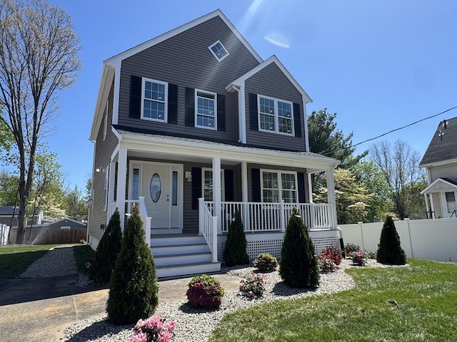 view of front facade featuring fence, covered porch, and a front lawn